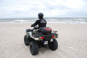 Fot. MOSG Funkcjonariusz Straży Granicznej patroluje czterokołowcem plaże.