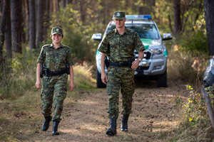 Fot. A. Kubiak Funkcjonariusze SG w trakcie patrolu pieszego w lesie. Za ich plecami samochód SG.