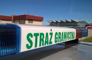 Fot. MOSG Napis Straż Graniczna na belce samochodu stojącego na płycie lotniska.