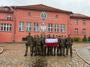 Fot. MOSG Funkcjonariusze stoją z polską flagą.