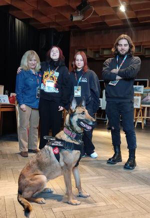 Pokaz psa służbowego w Ustce Zdjęcie pokazuje psa służnowego Straży Granicznej na tle osób kwestujących na rzecz Wielkiej Orkiestry Świątecznej Pomocy